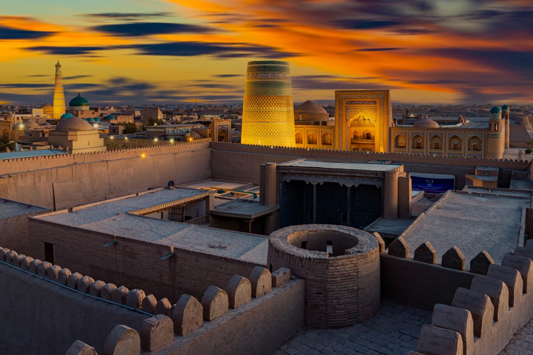Vista panorámica nocturna de Jiva (Khiva) con minaretes iluminados y muralla de Ichan Kala